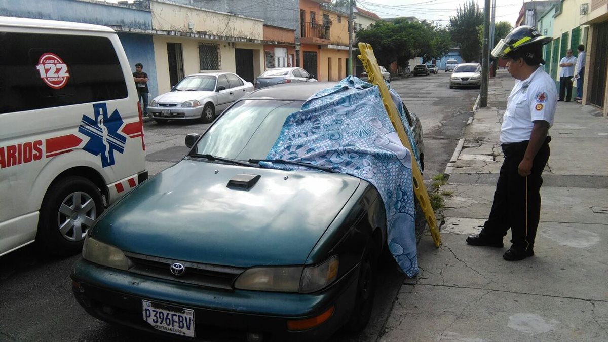 Un bombero cubre el cadáver de la víctima, baleada adentro de su vehículo, en la zona 11. (Foto Prensa Libre: Erick Ávila)