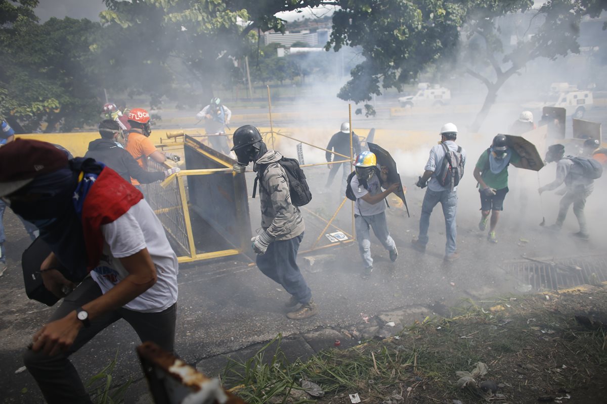 Opositores se ocultan durante los enfrentamientos con las fuerzas de seguridad. (AFP).