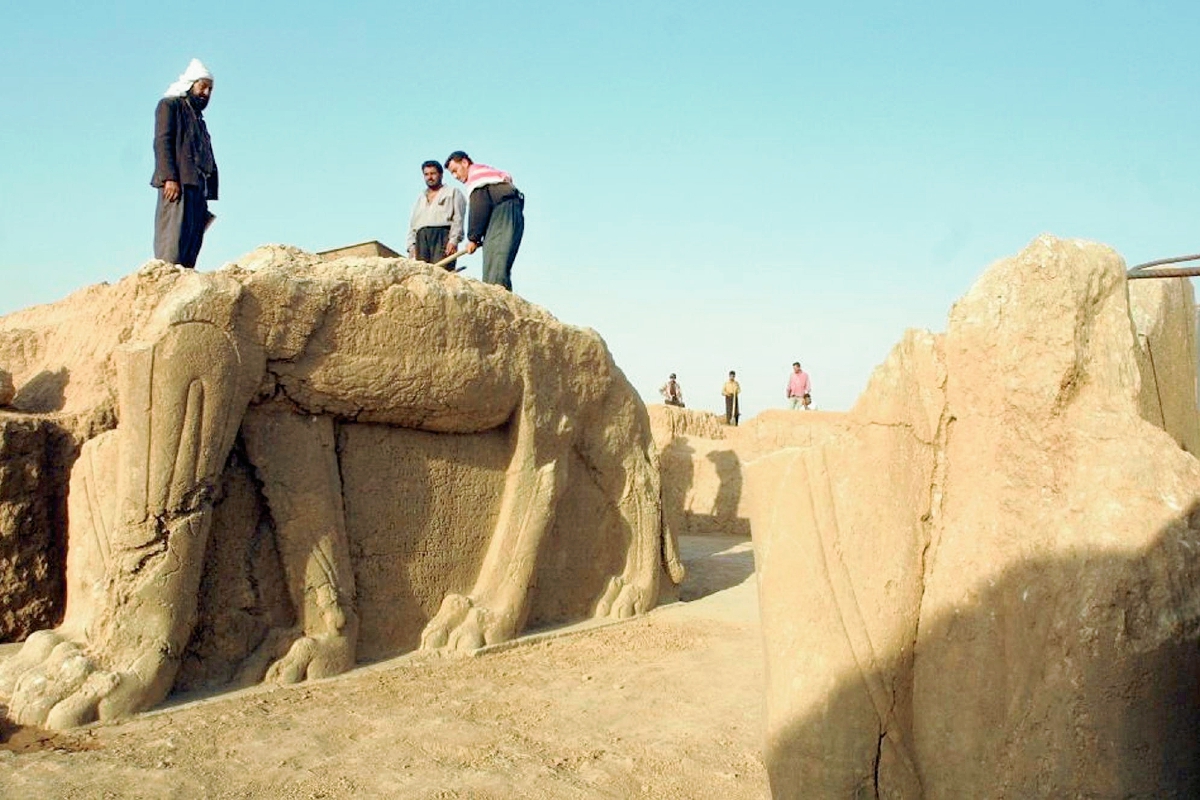 Trabajadores iraquíes  limpian una estatua en un sitio arqueólógico de Nimrud. (Foto Prensa Libre: AFP)