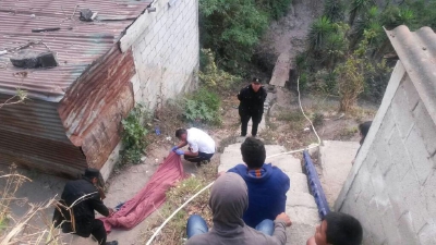 Agentes de la Policía Nacional Civil y Bomberos Voluntarios inspeccionan cadáver localizado en el kilómetro 15 de la ruta al Atlántico. (Foto Prensa Libre: PNC)