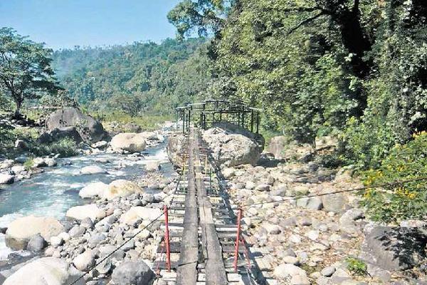 UN PUENTE colgante pasa sobre la ribera y parte del afluente