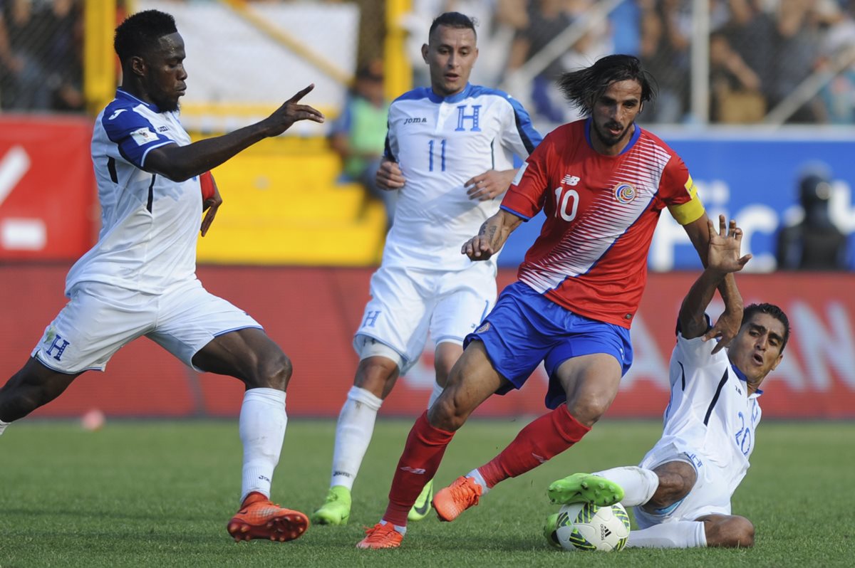 Bryan Ruiz intenta superar a dos rivales hondureños durante el encuentro que sostuvieron en San Pedro Sula, Honduras. (Foto Prensa Libre: AFP)