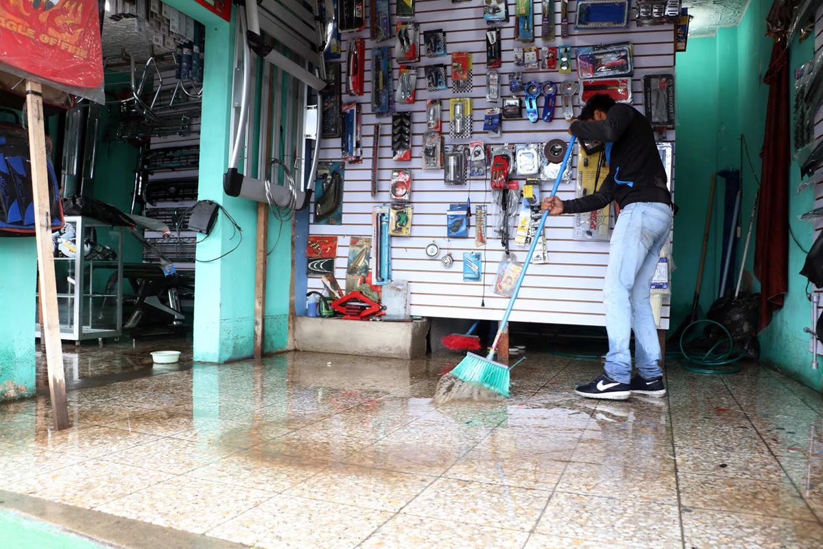 Comerciantes y vecinos de La Ciénaga, zona 2 de Xela, limpian el lodo que ingresó a sus viviendas la noche del miércoles último. (Foto Prensa Libre: Carlos Ventura)