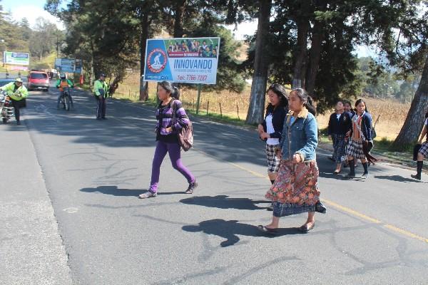 Agentes   de la PMT hacen alto a vehículos y dan paso a estudiantes, en la ciudad de Totonicapán.