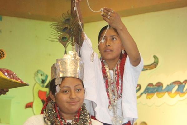 Nancy Viviana Tiul Cucul recibe la corona y el collar con la efigie de un pescado de parte de Marina Adela Cucul, señorita saliente. (Foto Prensa Libre: Ángel Martín Tax).