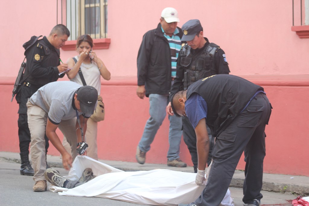 Fiscales del Ministerio Público cubren el cuerpo del maestro Nejimías Jonatán Salinas, el cual quedó a pocos metros de su negocio ubicado en la zona 3 de Cobán, Alta Verapaz. (Foto Prensa Libre: Ángel Tax)