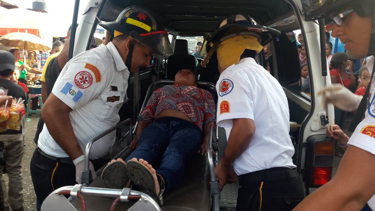 Socorristas trasladan a mujer embarazada que resultó golpeada por la carga de un autobús en Jalapa. (Foto Prensa Libre: Hugo Oliva)