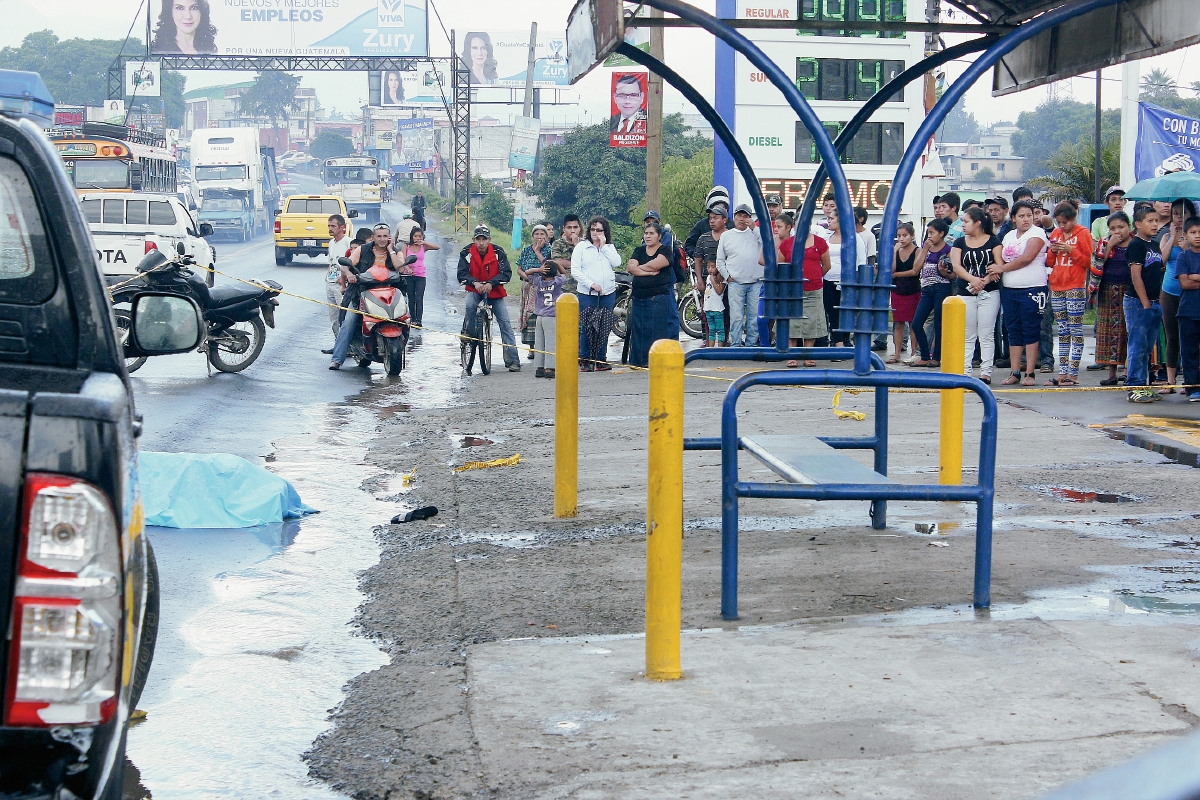 Curiosos observan el cadáver de Gerson David Pineda, quien murió baleado en El Tejar. (Foto Prensa Libre: Víctor Chamalé)