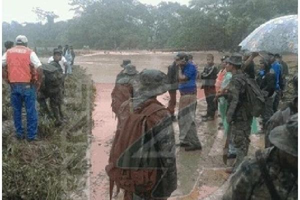 En imagen de un canal local, autoridades  observan un río que les impide llegar al área afectada.