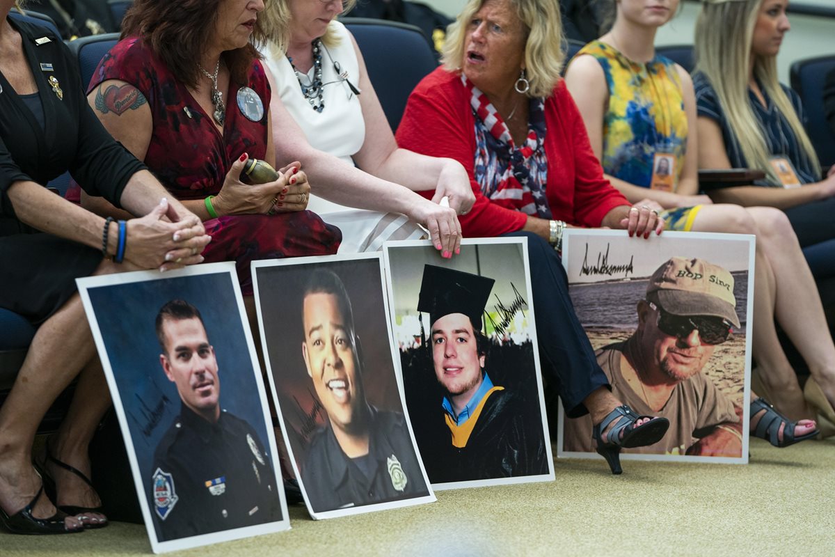 Padres de familia portan retratos de parientes muertos por inmigrantes criminales, mientras esperan a Trump que haga comentarios sobre migración. (AFP).