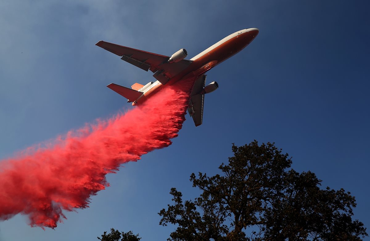 Un avión lanzaban agua encima de las llamas en Lakeport, California.(AFP)