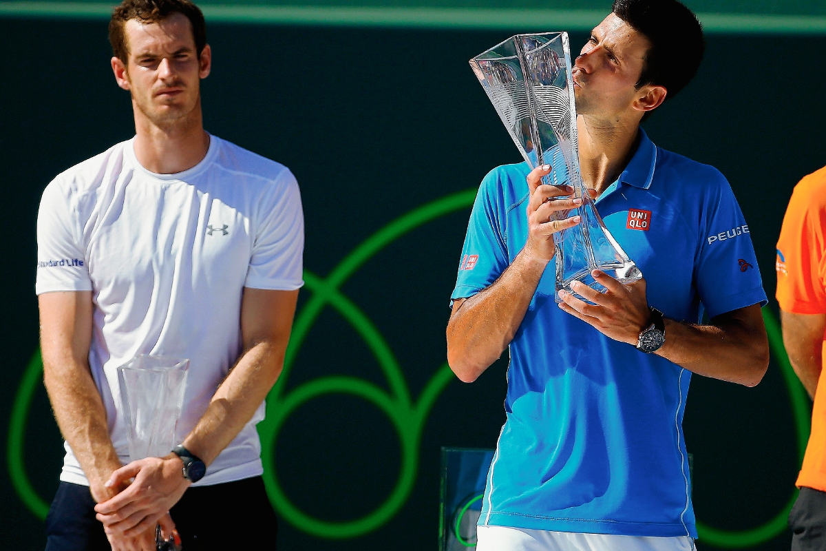 Novak Djokovic besa en trofeo de Miami ante la mirada de Andy Murray. (Foto Prensa Libre: AFP)