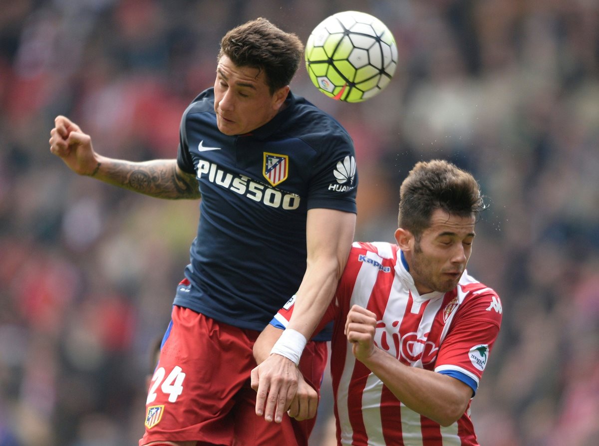 José María Giménez pelea el balón con Jony del Sporting Gijon durante el partido de este sábado. (Foto Prensa Libre: AFP)