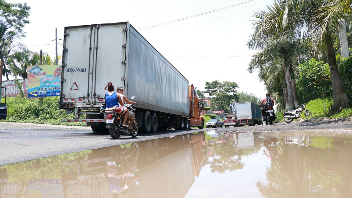 En la ruta al Pacífico se forman largas filas debido al bloqueo en el km 166. En primer plano se observa el mal estado de la carretera. (Foto Prensa Libre: Cristian Icó)