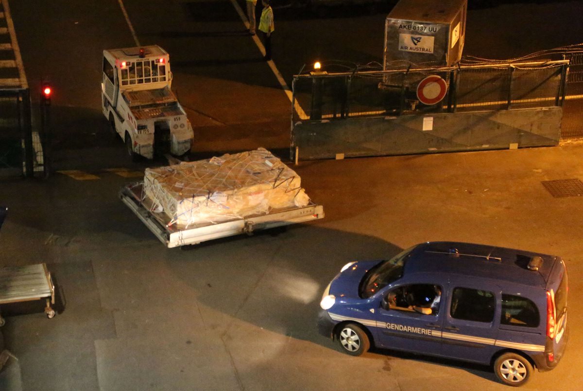 Policías escoltan la pieza del avión que fue encontrado en una isla francesa y que llegó a París para ser analizado. (Foto Prensa Libre: AFP).