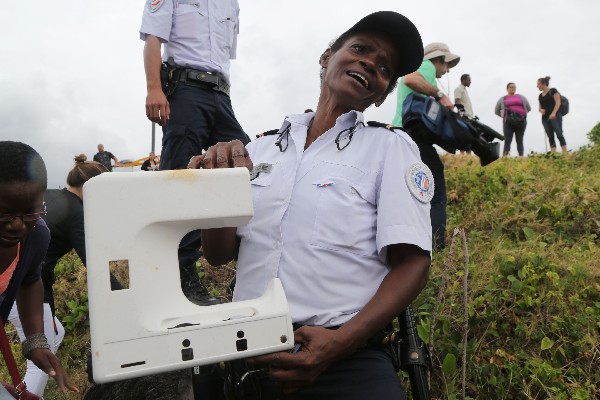 <em>Un policía sostiene una pieza plástica de una ventana del vuelo MH370. (Foto Prensa Libre:AFP).</em>