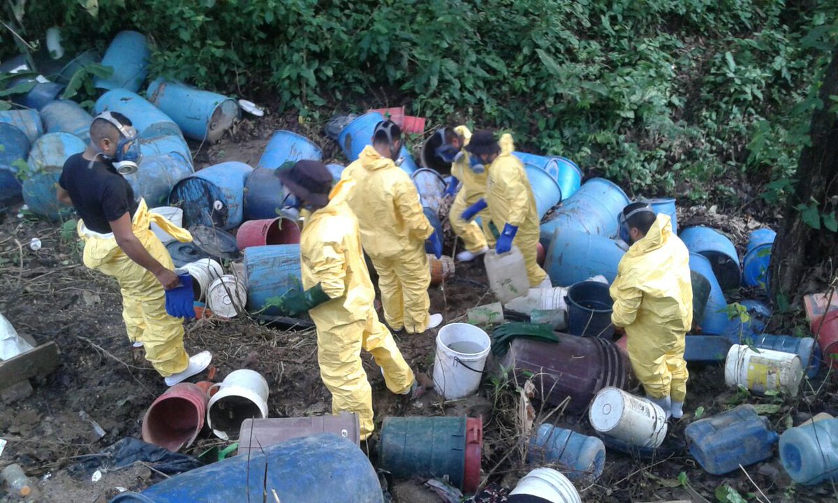 Agentes antinarcóticos efectúan exámenes en toneles localizados durante allanamiento en laboratorio de narcóticos, en Río Bravo. (Foto Prensa Libre: PNC)