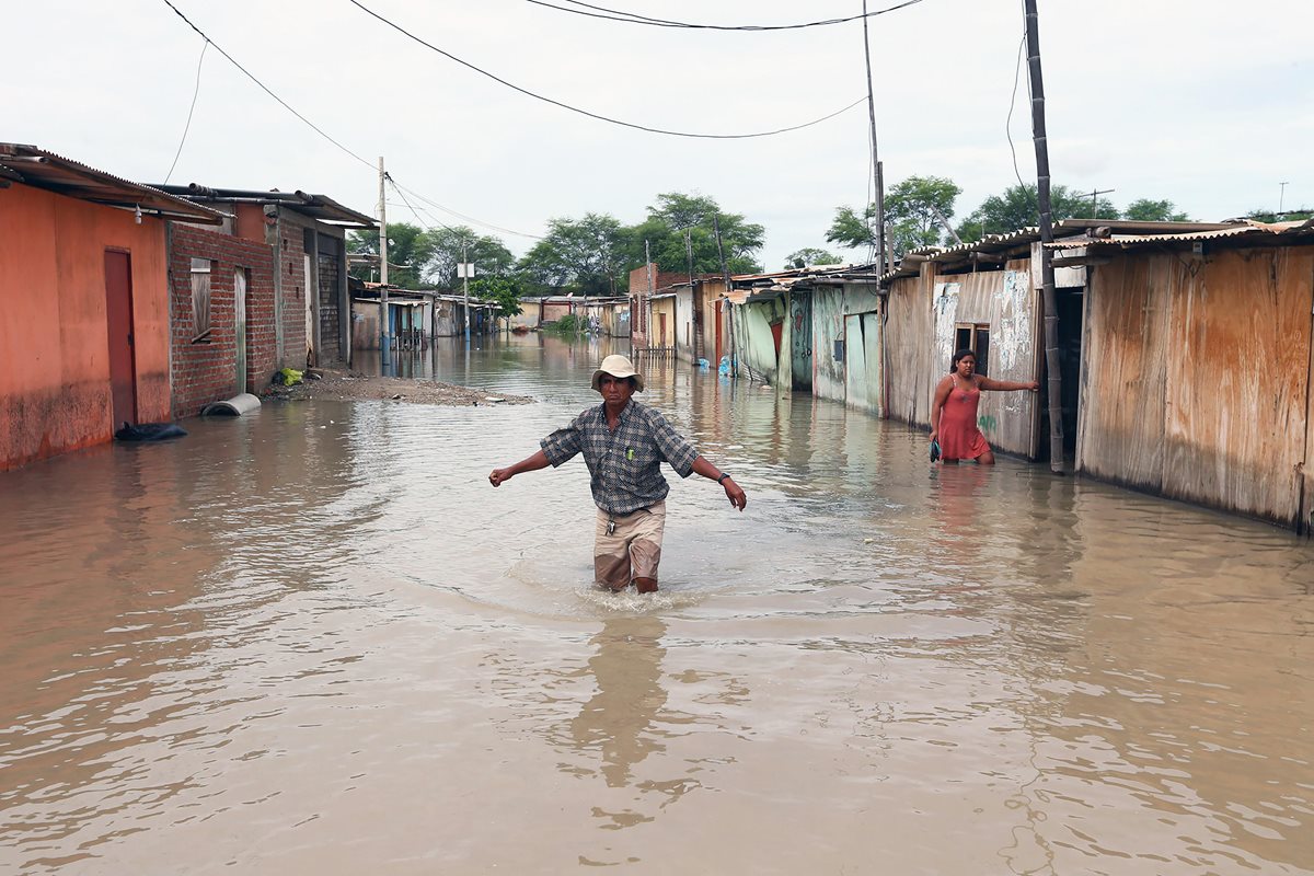 Un poblador trata de cruzar una calle inundada, en la región de Piura, costa norte de Perú. (Foto Prensa Libre: EFE/Elías Agustín)