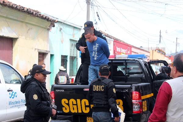 Agentes de la PNC bajan de un autopatrulla a otro de los detenidos, durante los operativos efectuados ayer.