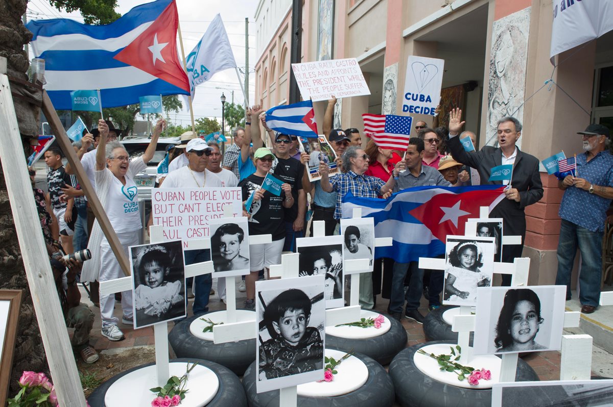 Vista de varias llantas con cruces blancas y fotografías de niños víctimas de la dictadura cubana durante una manifestación el domingo en el corazón de la Pequeña Habana, en Miami. (Foto Prensa Libre: EFE)