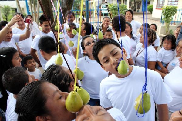 Menores tratan de morder pera, sin utilizar las manos.