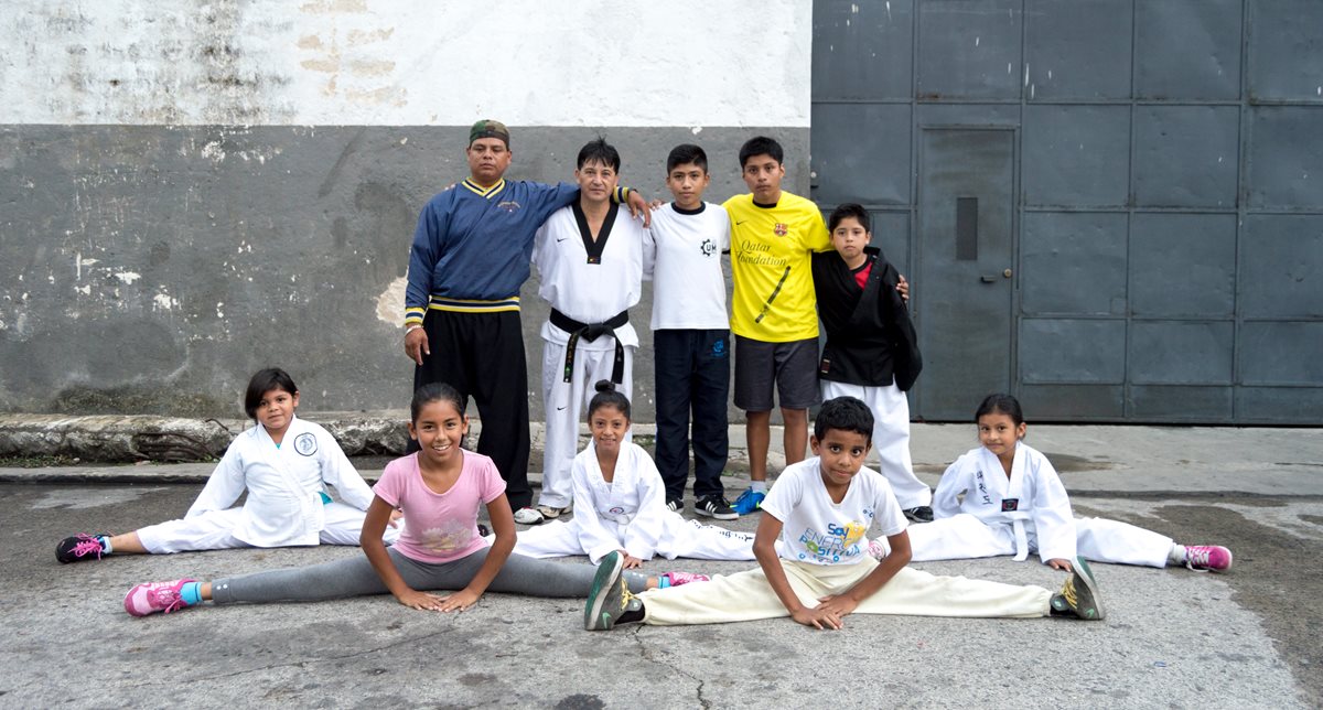 Los instructores Alfonso Gómez, con uniforme blanco y cinta negra, y Víctor Reyes —con sudadero azul— posan con algunos de sus discípulos. Foto Prensa Libre: Roberto Villalobos Viato. 