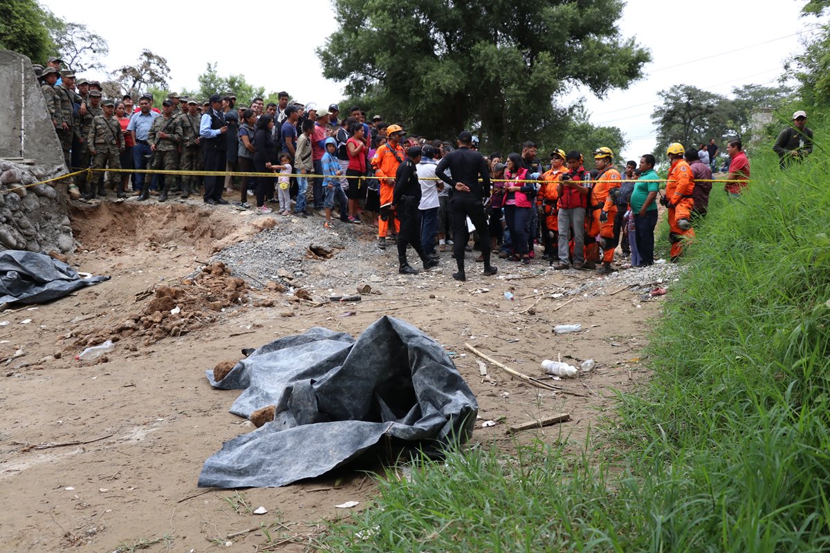 Curiosos se aglomeran en el área donde ocurrió el hallazgo y ven al cuerpo cubierto por nailon negro. (Foto Prensa Libre: Mike Castillo)