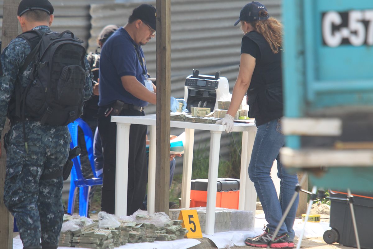 Fiscales y agentes antinarcóticos contabilizan el contenido de los paquetes de billetes de US$20, localizados en dos depósitos de combustible de camión. (Foto Prensa Libre: E. Paredes)