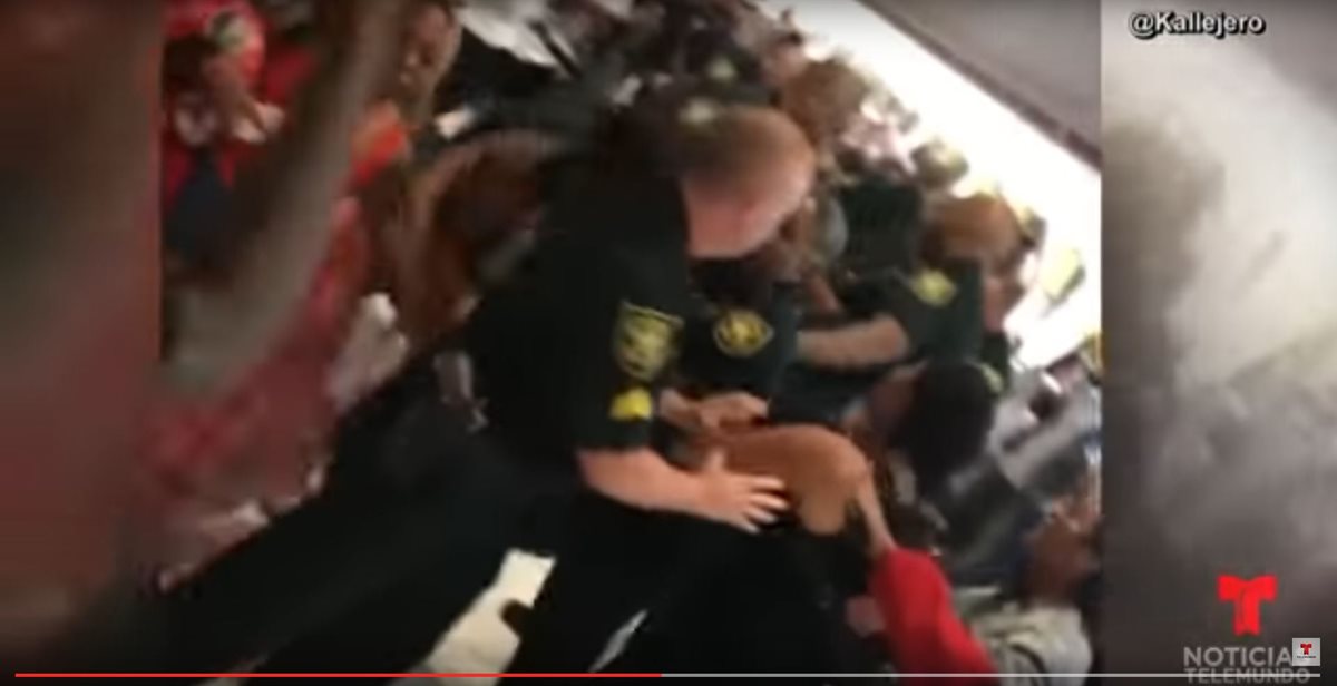Agentes policiales tratan de controlar a pasajeros de vuelos cancelados en un aeropuerto de Florida. (Foto Prensa Libre: Youtube Noticias Telemundo)