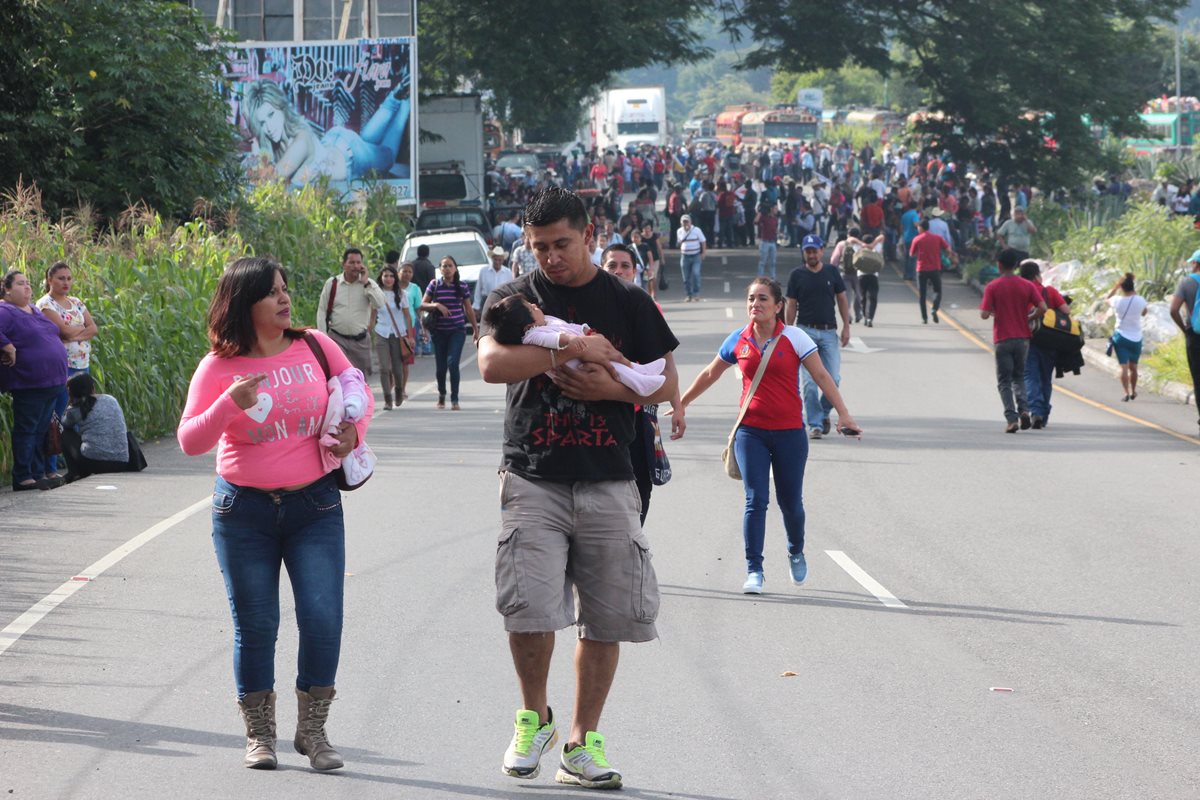 Un hombre carga a su bebé y atraviesa a pie el bloqueo que se encuentra en el Boquerón, Santa Rosa. (Foto Prensa Libre: Hugo Oliva)