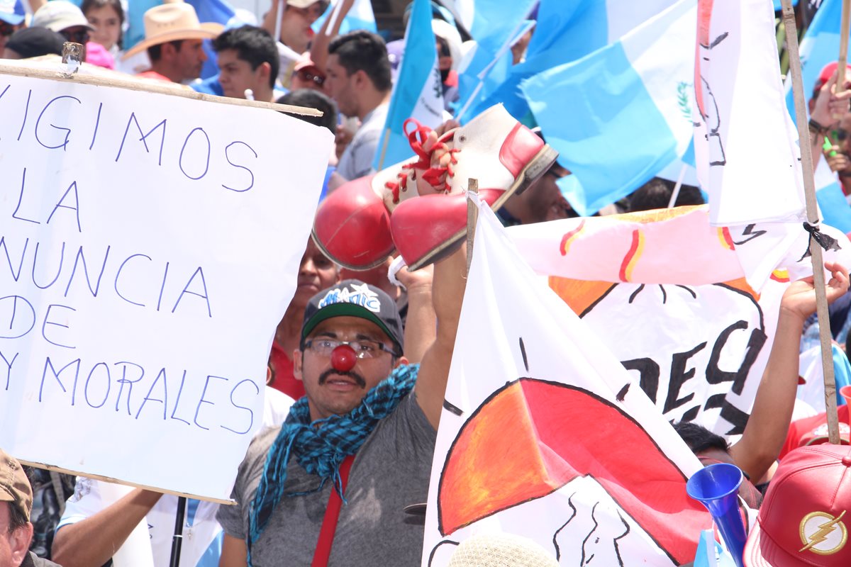 Un hombre sostiene un par de zapatos de payaso y usa una nariz roja en protesta por el Gobierno de Jimmy Morales (Foto Prensa Libre: Pablo Juárez)