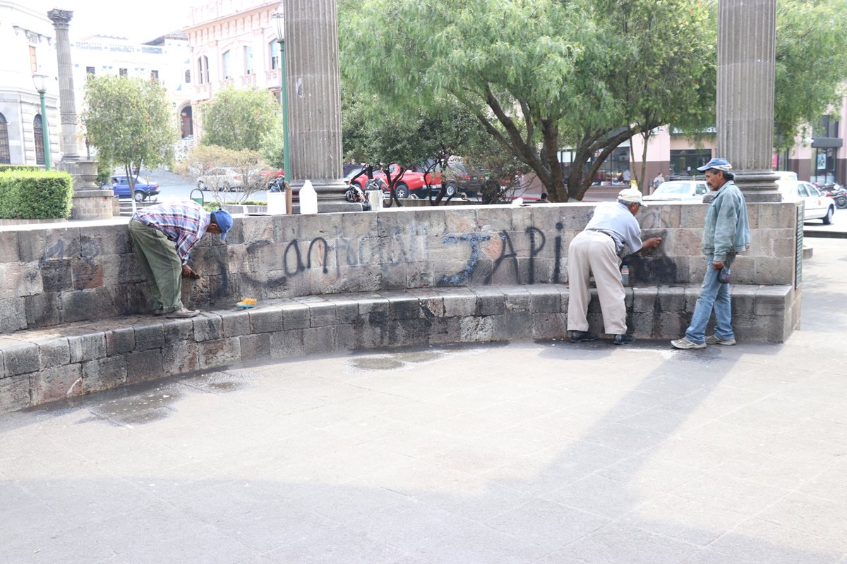 Trabajadores de la municipalidad limpian diferentes pintas en el parque central de Xela. (Foto Prensa Libre: María José Longo).