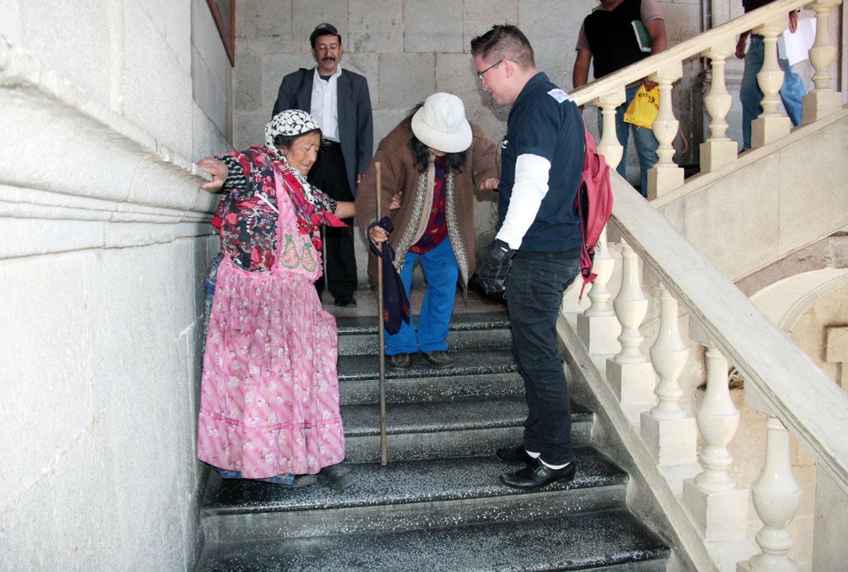 Un joven ayuda a dos mujeres de la tercera edad a bajar las gradas la comuna quetzalteca. (Foto Prensa Libre: Carlos Ventura)