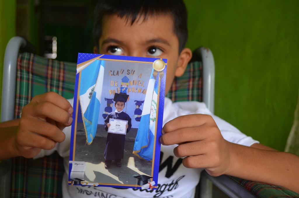 Jesús Alberto Grajales, quien permanece en silla de ruedas, muestra una fotografía tomada en su escuela, previo al incidente. (Foto Prensa Libre: Jorge Tizol).