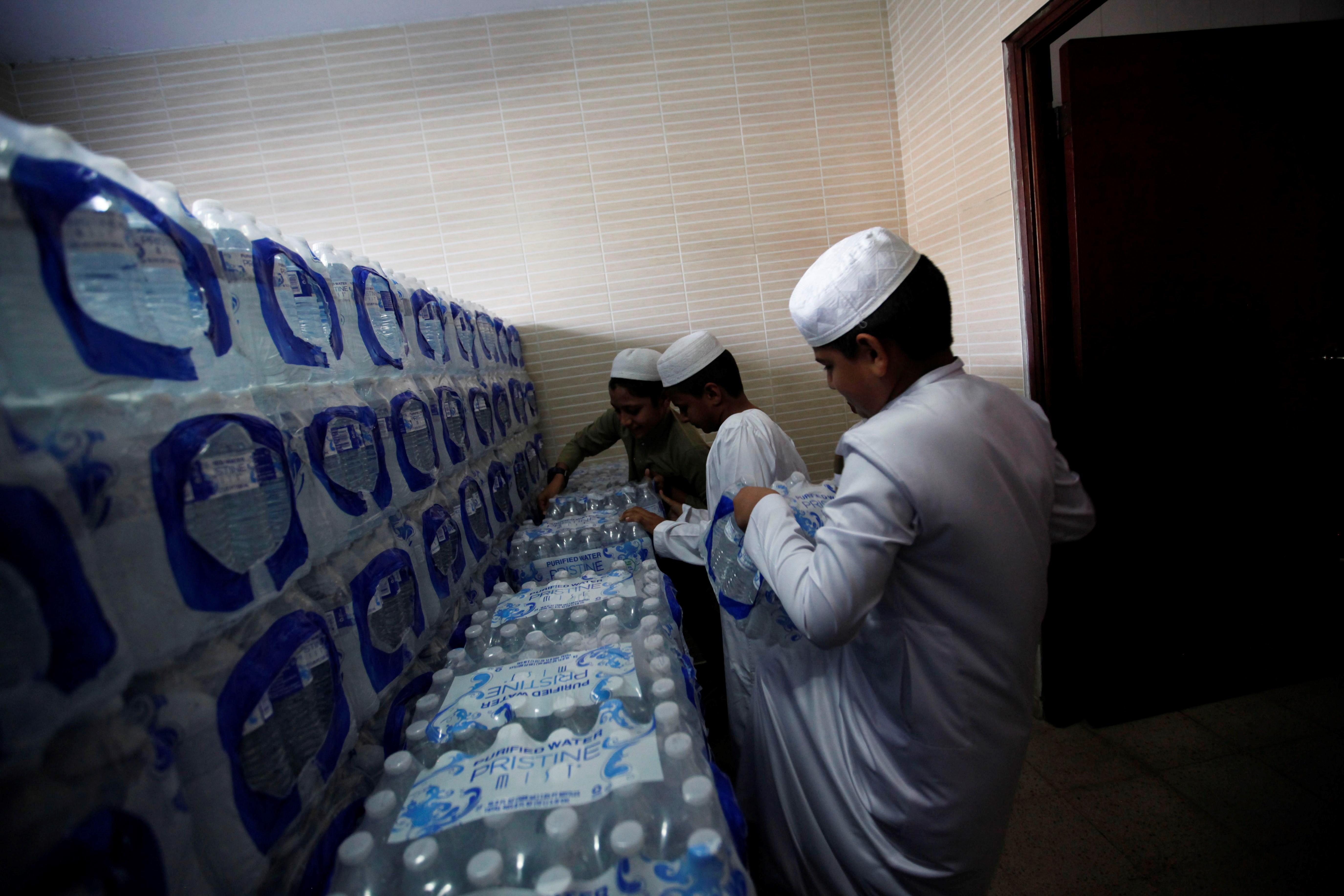 Niños musulmanes estiban cajas de agua en la mezquita de la fundación islámica Jummah Masjid. (Foto Prensa Libre: EFE)