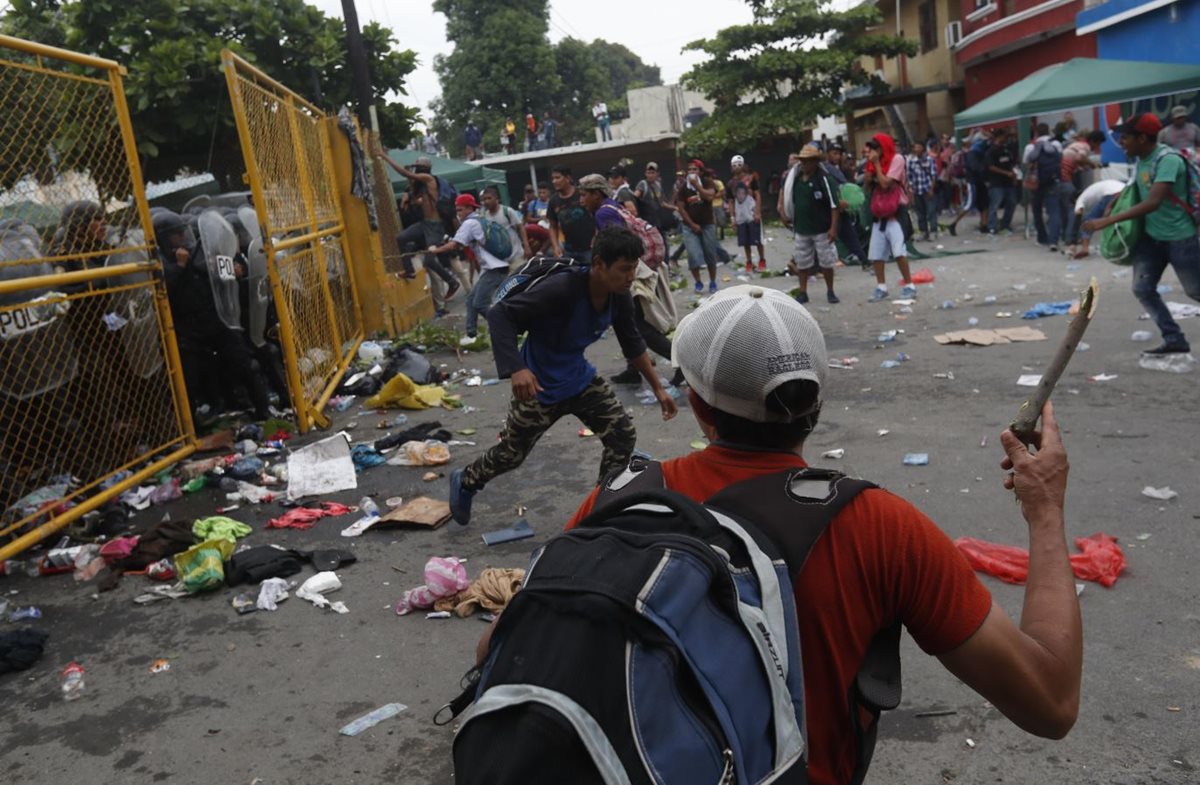 Migrantes hondureños se enfrentan a agentes de la Policía Nacional Civil quienes impiden el paso en la frontera entre Guatemala y México. (Foto Prensa Libre: EFE)