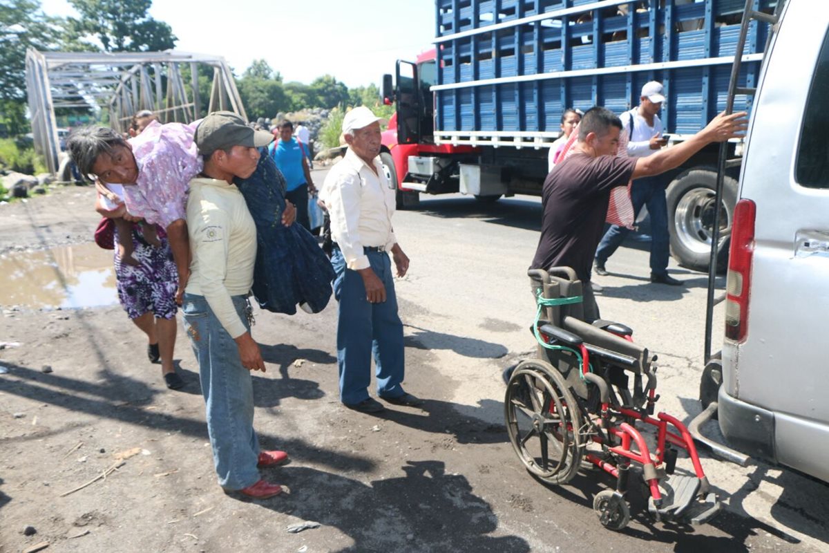 Una mujer enferma es llevada en hombros por su hijo, debido a bloqueos en ruta a suroccidente. (Foto Prensa Libre: Rolando Miranda)