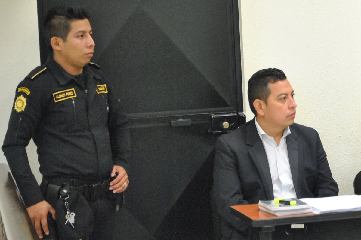 Byron Sales Curiel, el pastor evangélico condenado por defraudación, es custodiado por un policía durante la sentencia. (Foto: Prensa Libre)