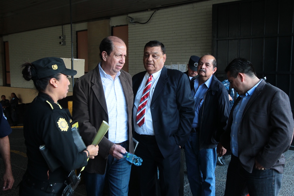 Una agente de la Policía Nacional Civil informa a José Luis Mijangos, Carlos Herrera, Edgar Cristiani y Alfredo Rabbé —al fondo— sobre su traslado a prisión. (Foto Prensa Libre: Álvaro Interiano)