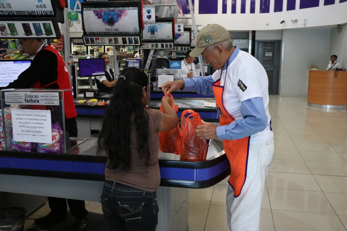 Jacobo Flores Cifuentes, de 80 años, ayuda a los clientes de La Torre, en Xela, a empacar los productos que compraron. (Foto Prensa Libre: María José Longo)