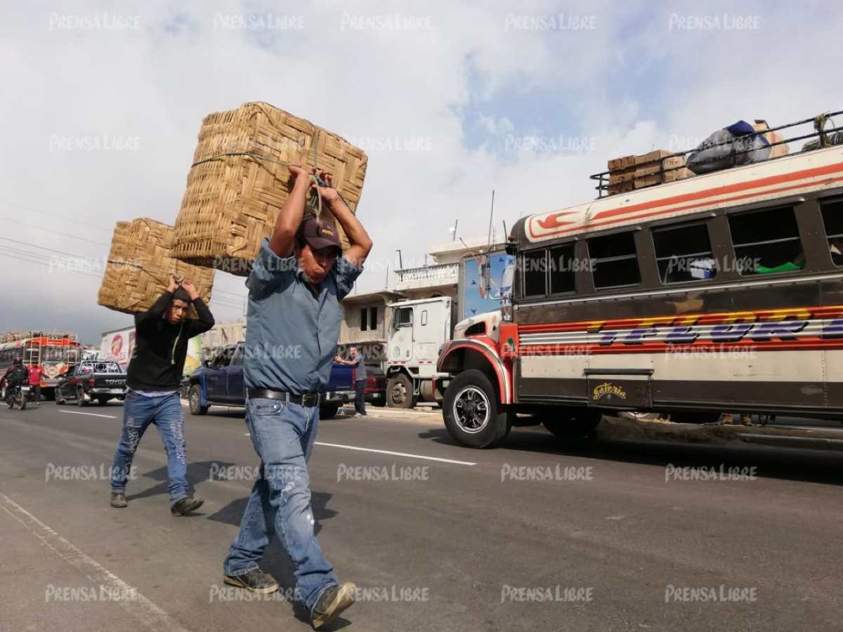 Algunas personas cargan bultos ante la paralización del tránsito vehicular.