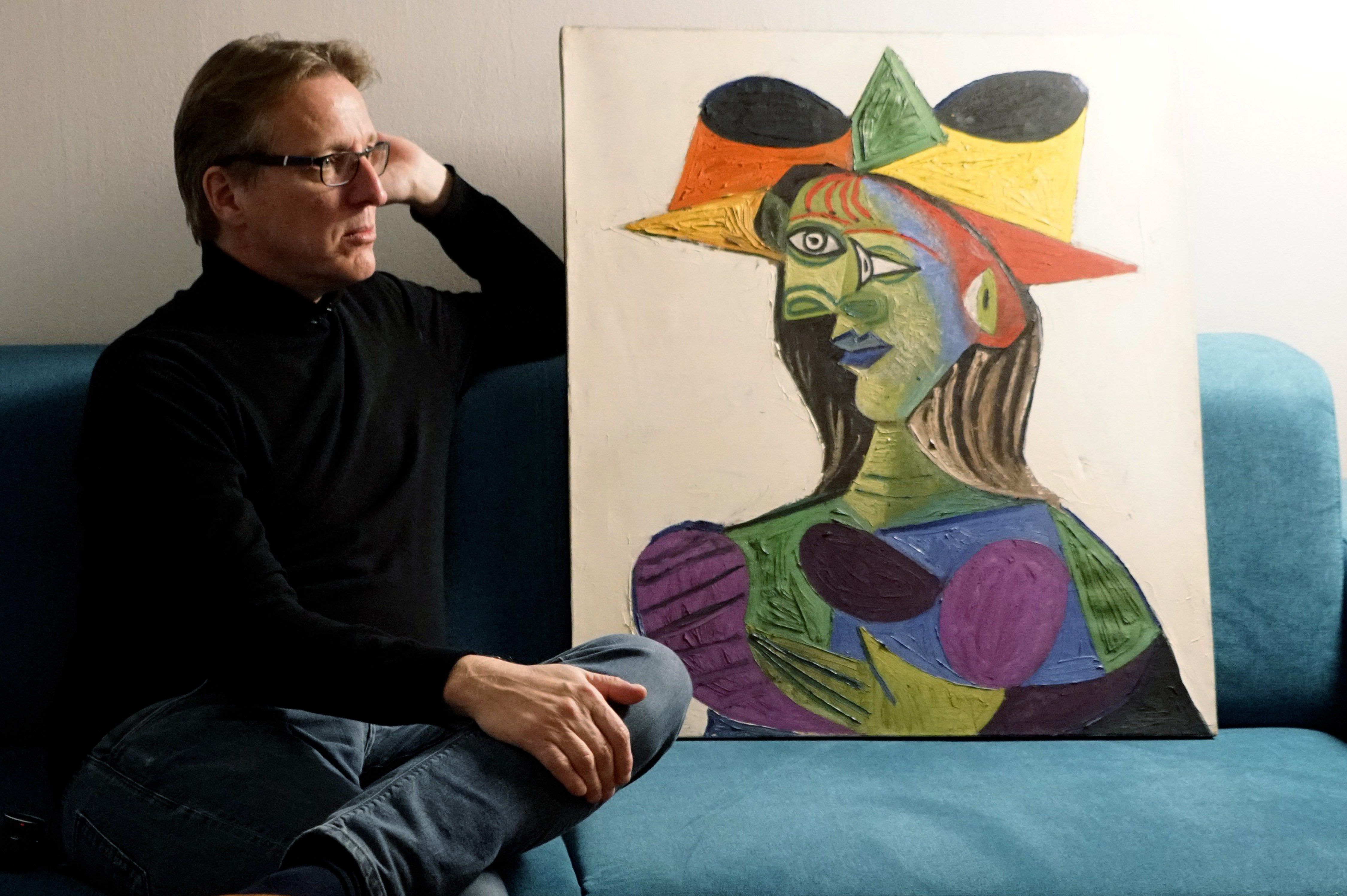 Arthur Brand sentado junto a la pintura "Busto de mujer", un cuadro que fue hallado 20 años más tarde de haber sido robado. (Foto Prensa Libre: EFE)