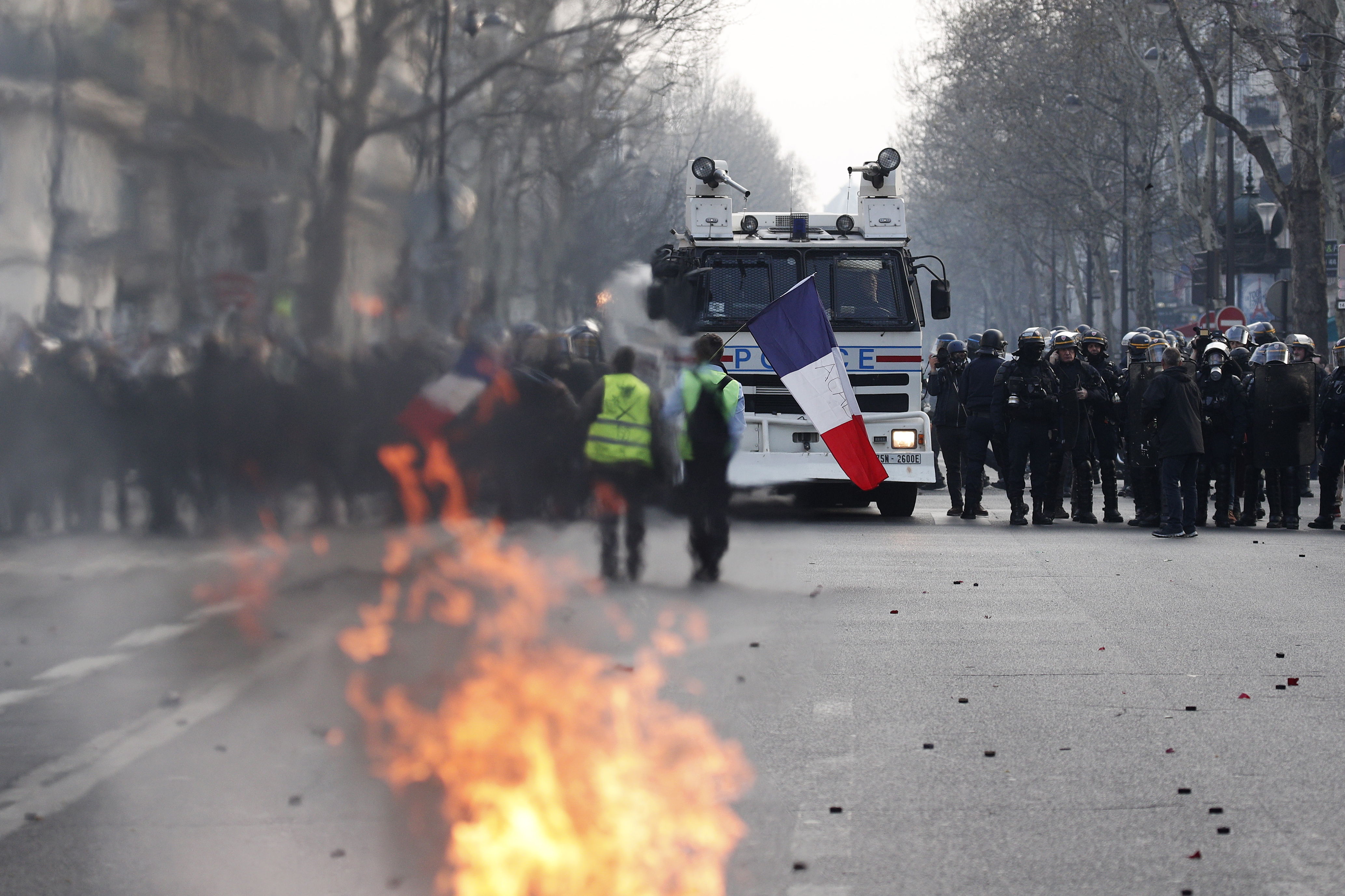 Los manifestantes del movimiento Chalecos Amarillos que sostienen una bandera francesa se enfrentan a los policías antidisturbios franceses durante los enfrentamientos como parte de la manifestación. (Foto Prensa Libre: EFE).