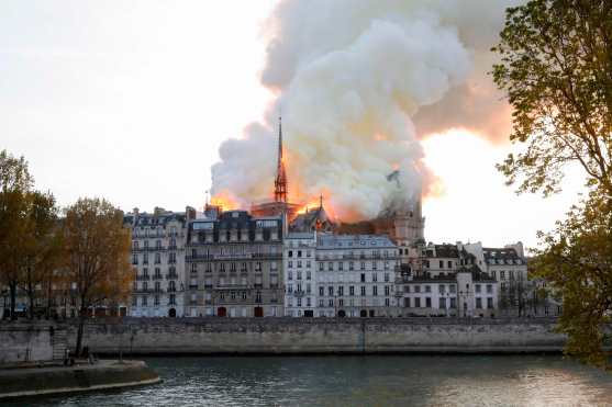 Humo y llamas salen desde la catedral de Notre-Dame, vista desde el río Sena. (Foto Prensa Libre: AFP)