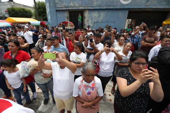 Vecinos graban la salida de la procesión. 