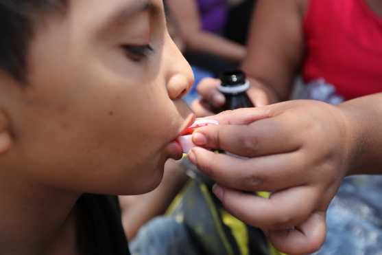 En una parada un niño toma su medicina para la toz. 