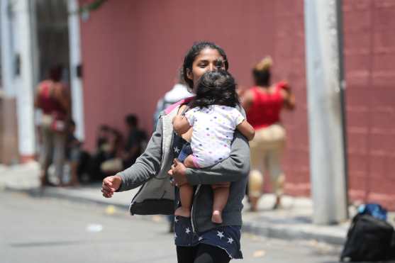 Una mujer viaja con su hija en brazos.