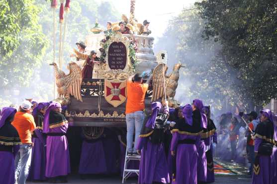 Una persona coloca una ofrenda de flores en el anda de Jesús de los Milagros. 