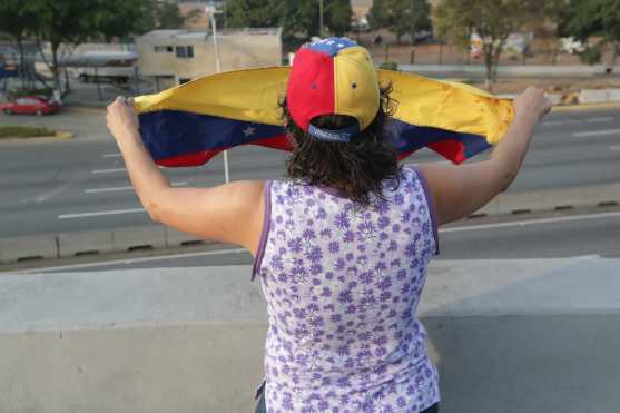 Una mujer despliega una bandera en la base de La Carlota, al este de Caracas, donde ha sido conducido el opositor Leopoldo López, tras ser liberado este martes y donde se ha reunido con el presidente nombrado Juan Guaidó, que ha anunciado que los militares han dado el paso para unirse a él. Foto Prensa Libre: EFE