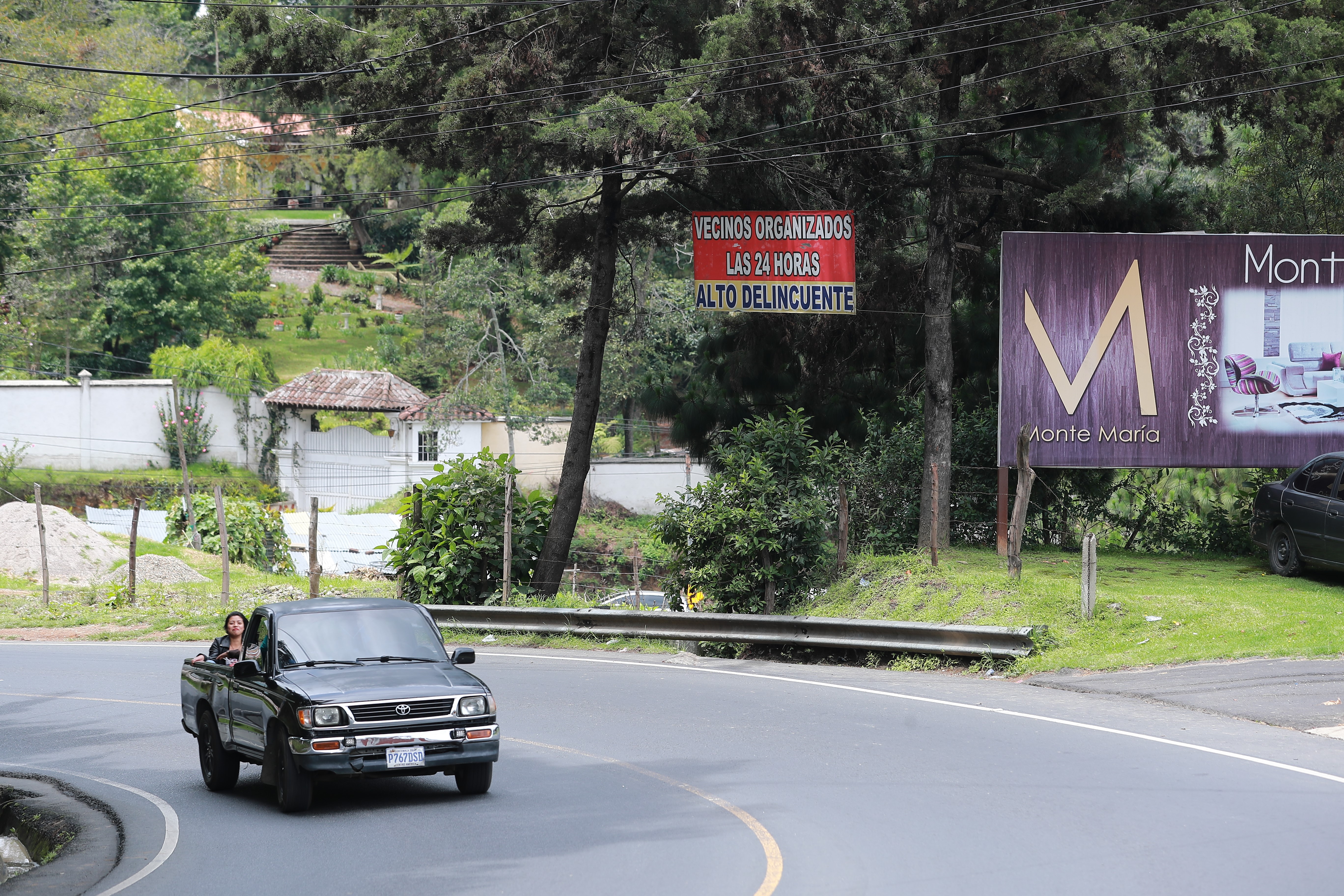 Un kilómetro antes de llegar al centro urbano de San Juan Sacatepéquez un rótulo colgado en un poste de energía eléctrica, en la ruta principal,  advierte de "vigilancia a delincuentes". (Foto Prensa Libre: Juan Diego González) 